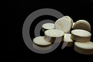 Pills on a black background. Focus on foreground, soft bokeh