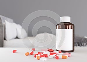 Pills and blank bottle on table at home. Medicines, tablets. Sick to be. Stay in bed. Medical bottle mock up. Illness