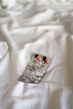 Pills in a blister pack on a bed