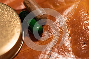 Pills and a bottlecap on a brown leaf