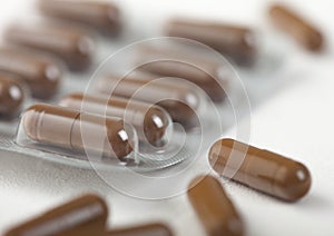 Pills capsule in plastic strip on white background. Antibiotics, vitamins, painkiller. Brown color