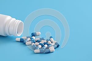 Pills capsules with bottle isolated on blue background