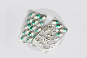 Pills capsules in the package on grey background. White and green tablets. Concept of health and medicine. Full and empty packagin