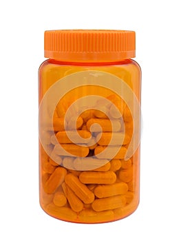 Pills and capsules in a plastic medical small bottle of orange color with a cover isolated on a white background