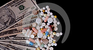 Pills on dollar money isolated on black background. Medicine expenses. High costs of medication concept