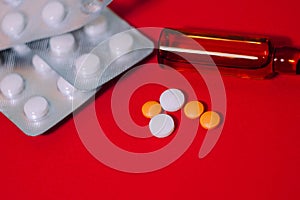 Pills and drugs blisters and ampoule on red background. Healthcare wallpaper. Medical package