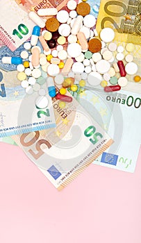 A pills and euro on a pink background with copy space. Soft focus. Concept of medicine, money and health