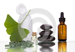 Pills with extract from the ginkgo in bottle and green leaves isolated on a white background photo