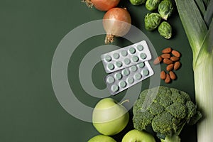 Pills and food on green background, flat lay with space for text. Prebiotic supplements