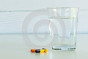 Pills and a glass of drinking water isolated on the white table