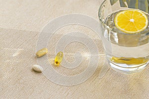 Pills and a glass of water with lemon. Health care and morning routine concept. Supplements and vitamins