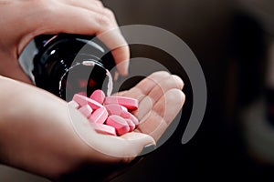 Pills in hand, pink vitamins