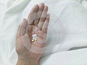 Pills in the hands of the patient on the bed