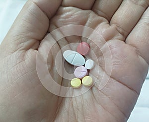 Pills in the hands of the patient on the bed