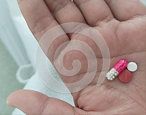 Pills in the hands of the patient on the bed