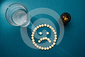 The pills are laid out on a blue background in the form of a sad emoticon.