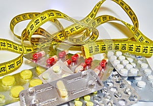 Pills with measuring tape, represent the diet pill industry. Diet meds concept