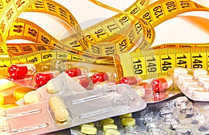 Pills with measuring tape, represent the diet pill industry. Diet meds concept