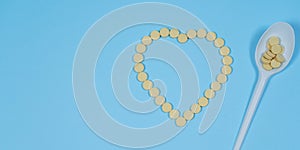 Pills - medicines are poured in the form of heart on a blue background and spoon