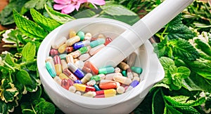 Pills in a mortar on a fresh herbs background