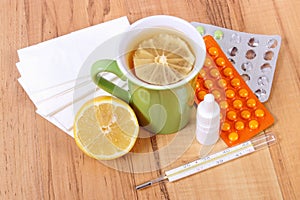 Pills and nose drops for colds, handkerchiefs and hot tea with lemon