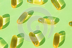 Pills of omega 3 close up on pastel green background with shadow. Health care concept. Supplements and vitamins. Top view. Flat