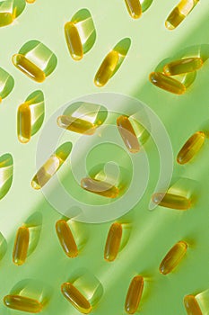 Pills of omega 3 close up on pastel green background with shadow. Health care concept. Supplements and vitamins. Top view. Flat
