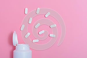 Pills with an opened white bottle, close up.