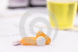 Pills and oral urinary incontinence medication, with urine bottle in the background, testing lab
