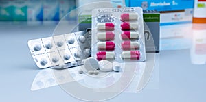 Pills in pharmacy shop. White tablets pills on blurred capsule in blister pack and white tablets pills in pack near drug box