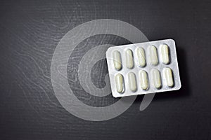 Pills in plastic white packaging on black background