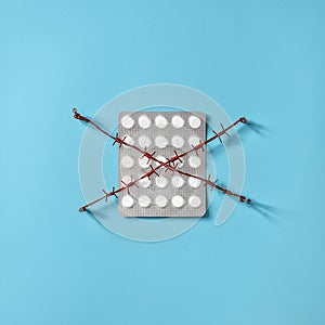 Pills with red barbed wire. Concept for the theme of human dependence on drugs, painkillers and antidepressants