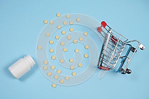 Pills in shopping cart on blue background. The concept: trade in medicines, pharmacies photo