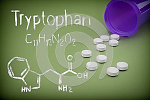 Pills spilling from an open bottle on green background, Chemical formulation of trytophan written with chalk