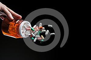 Pills spilling out of pill bottle on black background with copy space, Macro shot of pills being poured into a hand from a