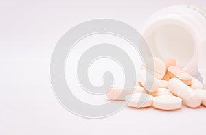 Pills spilling out of pill bottle on white background with copy space