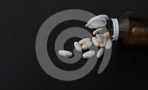 Pills spilling out of pill bottles isolated on black background