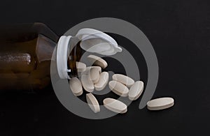 Pills spilling out of pill bottles isolated on black background