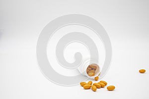 Pills spilling out of a white pill bottle against a white background