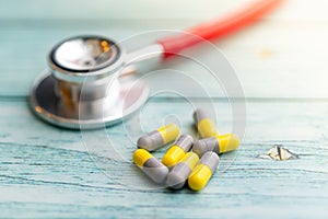 Pills with stethoscope on  wooden background. Shallow Depth of field