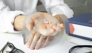 Pills, tablets and drugs pouring from bottle in doctor hand on