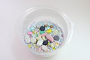 Pills, tablets and multicolored small round vitamin dragees inside plastic transparent dome lid of box for mini cake packing