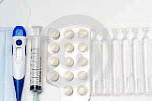 Pills, thermometer and syringes on white background. Coronavirus COVID-19 epidemic. Flat lay, top view, copy space