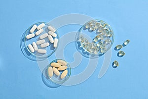 Pills of various colors and shapes are adorned on a petri dish against a green background.