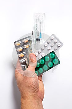 Pills for various diseases, a thermometer and a syringe in a personâ€™s hand