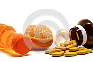 Pills of vitamin C, fresh orange fruit, and sweet drinking bottle on white background