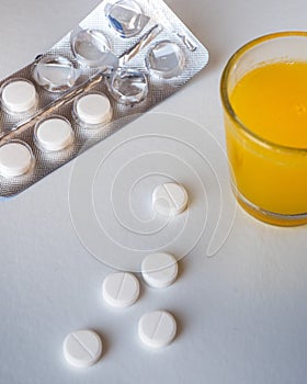 Pills on a white background and a glass of orange juice for the treatment of colds a diseases