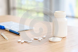 Pills with white plastic medicine bottle on the table