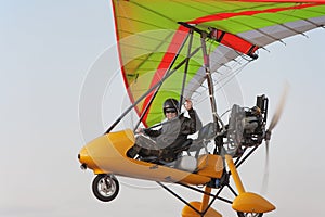 The pilot flies on a yellow motor hang-glider