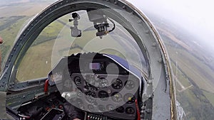 The pilot hold and control helm. A gray combat plane fly over field and rolls to the left. A fighter moves over a green forest